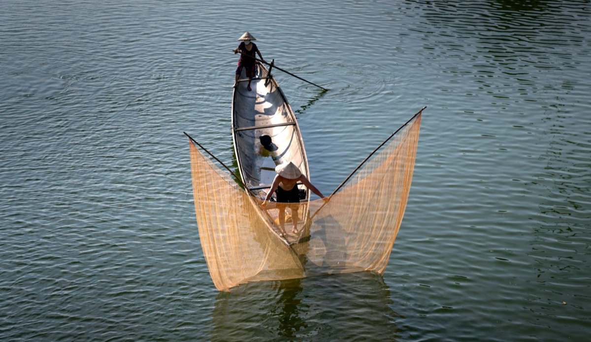 Fishing boat with net and rod in early morning light