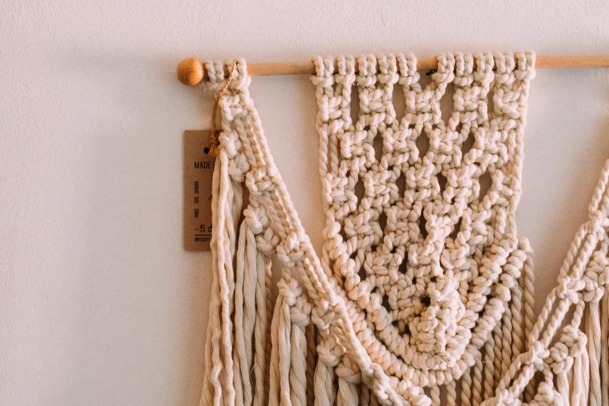 Detailed view of a handmade beige macrame wall hanging showcasing intricate knots and pattern.