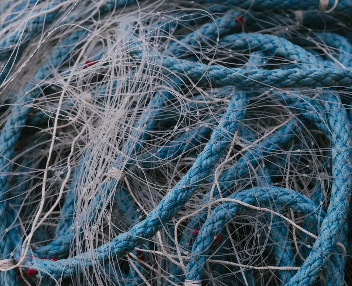 Detailed close-up of tangled blue rope and fishing nets, highlighting texture.