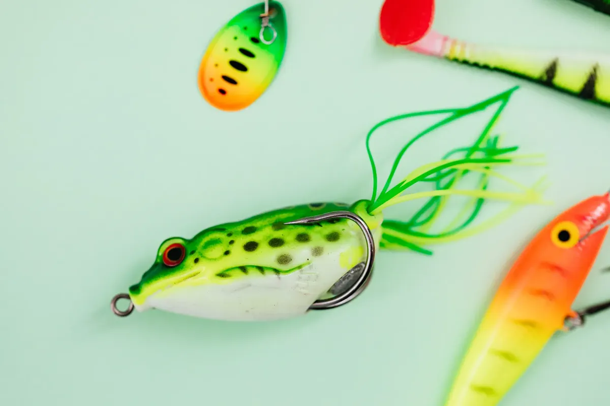 Vivid collection of fishing lures in various shapes and colors on a soft mint background.